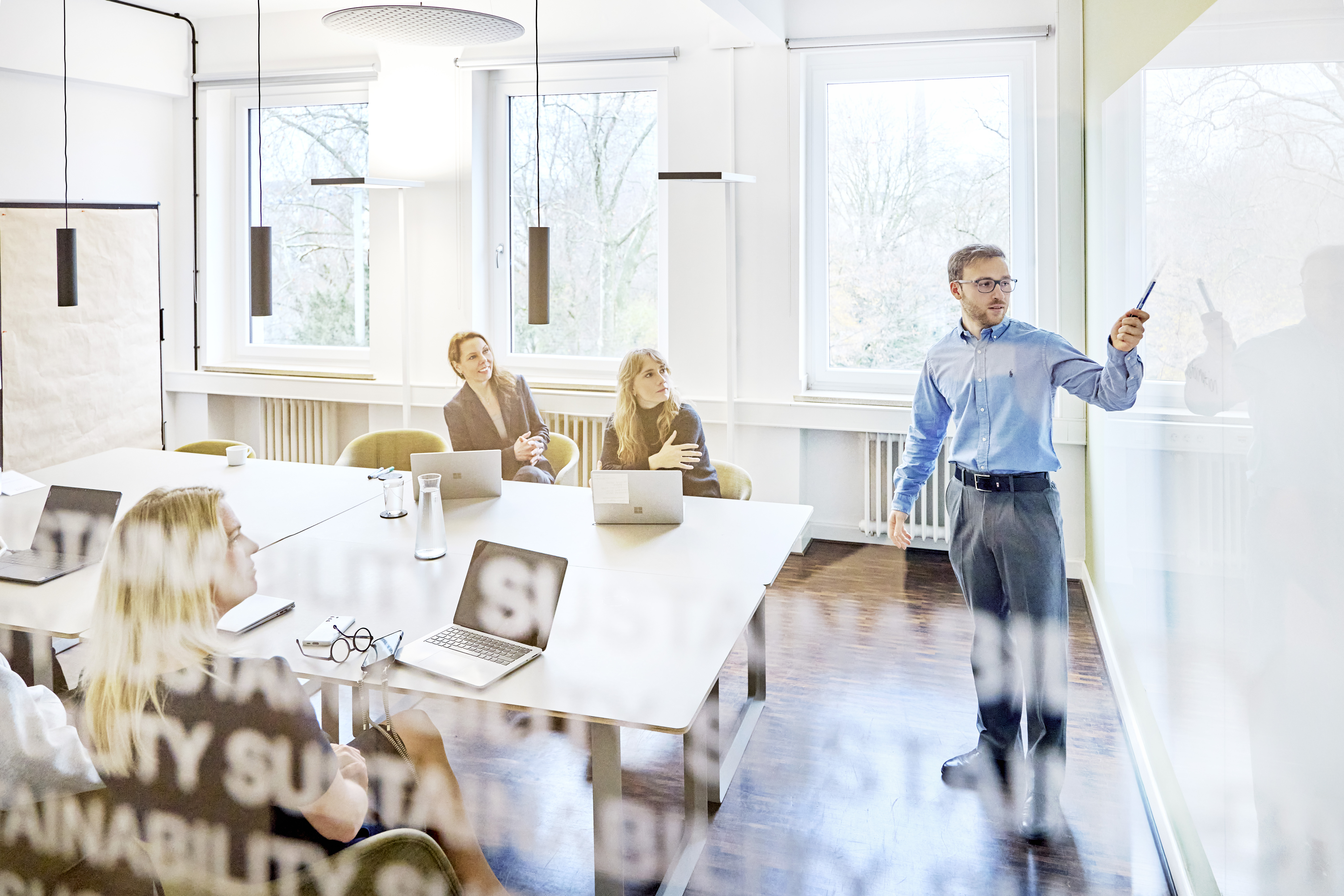 Mitarbeiter erklärt seinen Kolleg:innen etwas an einem Whiteboard.